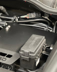 An MSD electronic module and a black plastic junction box mounted in a vehicle engine bay, surrounded by wiring and hoses.