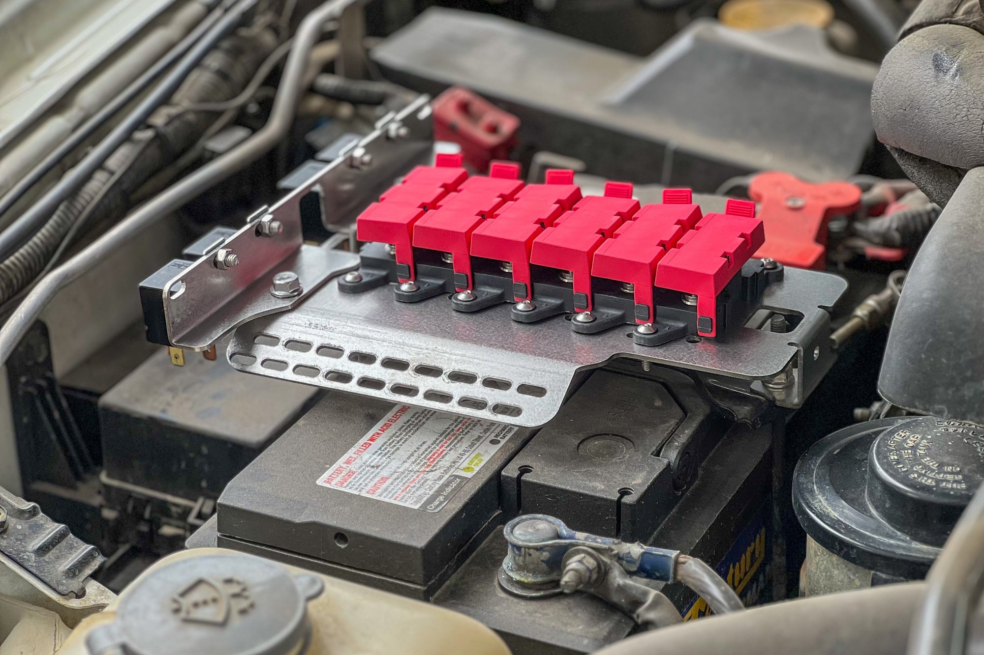 Battery bracket's accessory mounting kit installed on a car battery for 12-volt accessory organization.