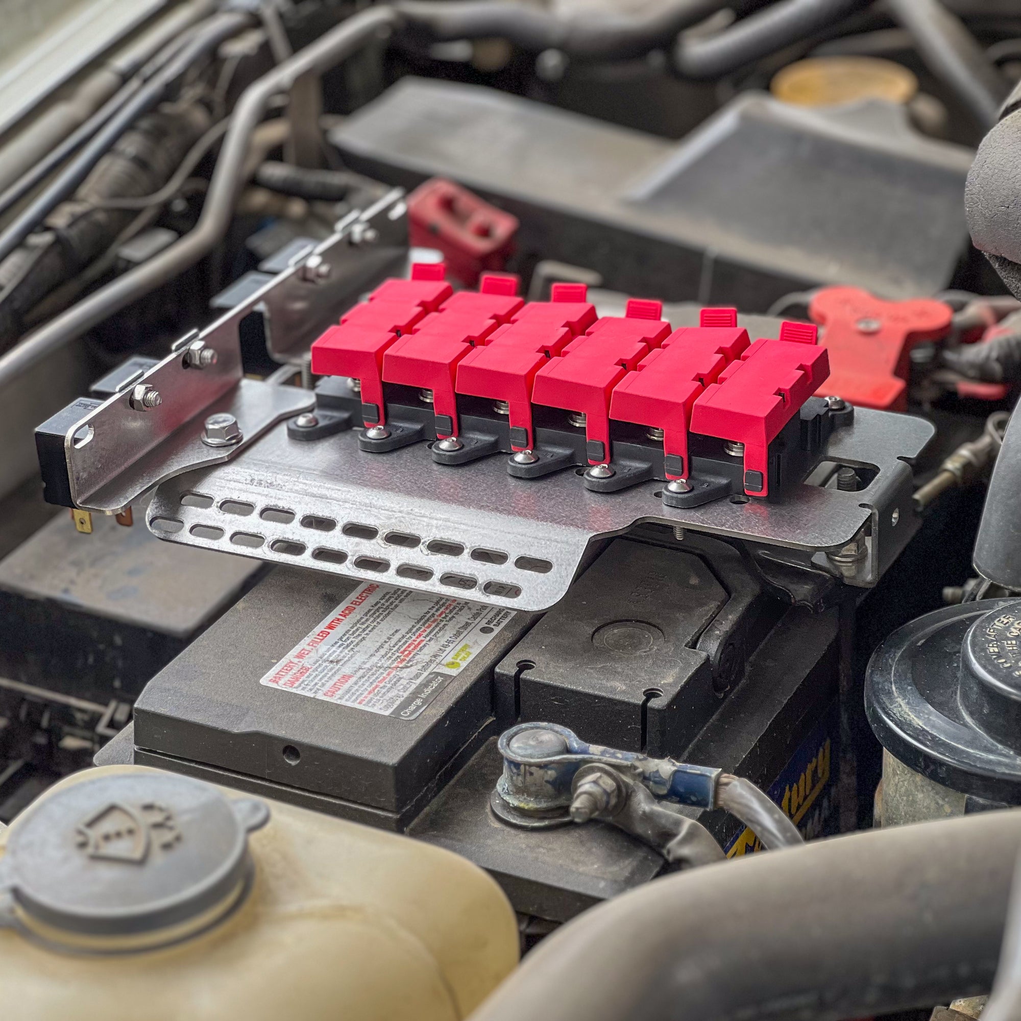 GU Patrol Battery Fuse Bracket installed on a vehicle battery, organizing wiring and fuses for efficient electrical system.