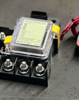 Blue Sea SafetyHub 100 Fuse Block next to wiring connector on a dark surface.